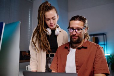 Bilgisayarda şifrelenmiş verilere bakan iki genç bilişim mühendisi ve karanlık ofiste gece buluşmalarında şifreyi nasıl çözeceklerini düşünüyorlar.