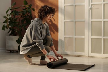 Spor kıyafetleri içinde spor kıyafetleri içinde spor yaparken oturma odasının zemininde çömelmiş otururken yan görünüm.