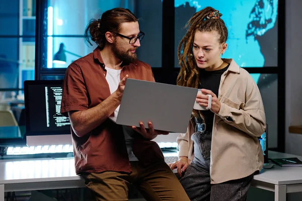 两名年轻的It工程师在笔记本电脑屏幕上讨论在线数据 而男人则用一杯咖啡解释女同事最简单的解码方法 — 图库照片