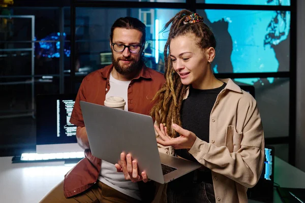 年轻自信的女性在办公室开会时向男性同事解释在线数据和解码方法时 指着笔记本电脑屏幕 — 图库照片