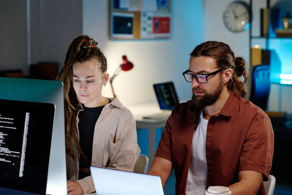 İki ciddi erkek ve kadın iş arkadaşı geceleri karanlık ofisteki bilgisayarların önünde oturmuş veri deşifre ediyorlar.