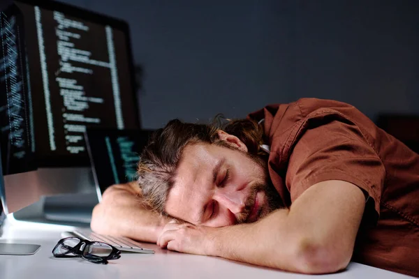 新しいデコードソフトウェアを開発した後 コンピュータキーボードの睡眠で机の上に彼の頭を持つ若い疲れ男性プログラマー — ストック写真