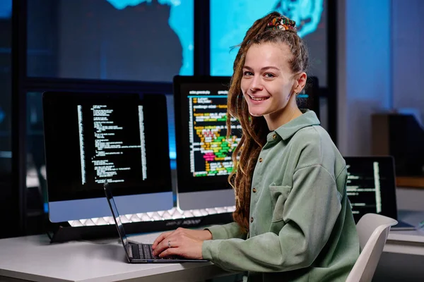 若い成功した女性プログラマーは デスクトップコンピュータのグループと職場でカメラを見て 画面上のコード化されたデータを持つ — ストック写真