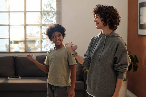 快乐的年轻女子和她可爱的儿子穿着运动服 站在镜头前练习哑铃 — 图库照片