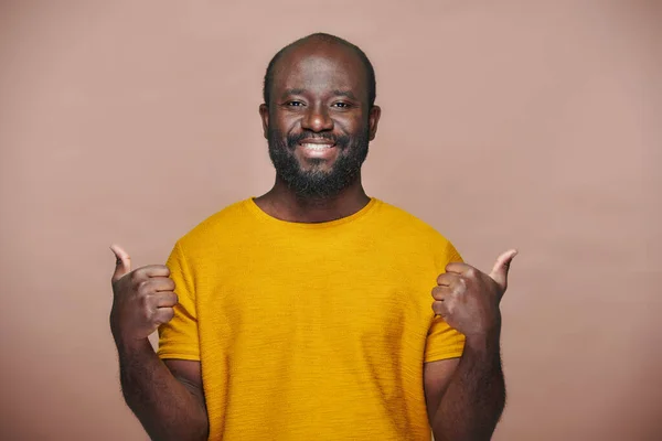 身穿黄色T恤的非裔美国人的画像 大姆指翘起 在镜头前微笑 — 图库照片
