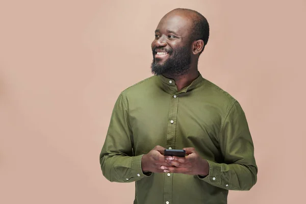 Portret Szczęśliwego Afroamerykanina Korzystającego Smartfona Uśmiechniętego Stojącego Brązowym Tle — Zdjęcie stockowe