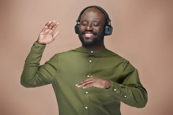 Feliz Hombre Afroamericano Escuchando Música Auriculares Inalámbricos Bailando Fondo Marrón — Foto de Stock