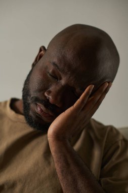 Gri arka planda başı ağrıyan Afrikalı Amerikalı bir adamın dikey görüntüsü