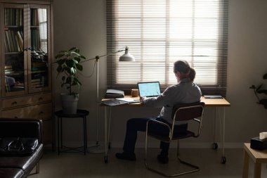 Yetişkin erkek psikoloğun ofisinin yanında dizüstü bilgisayarının önünde oturup başı belada olan bir sonraki hastayı beklemesi.