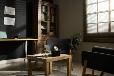 Bir bardak su ve psikoterapist hastalar için kağıt mendil içeren kutuyla çevrili iki rahat koltuk.