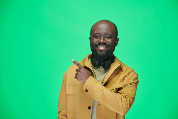 Портрет Афроамериканського Чоловіка Жовтій Куртці Вказує Порожній Простір Посміхається Камері — стокове фото