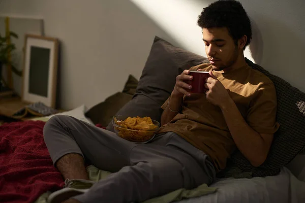 Guy Desfrutando Café Quente Batatas Fritas Enquanto Relaxa Cama Seu — Fotografia de Stock