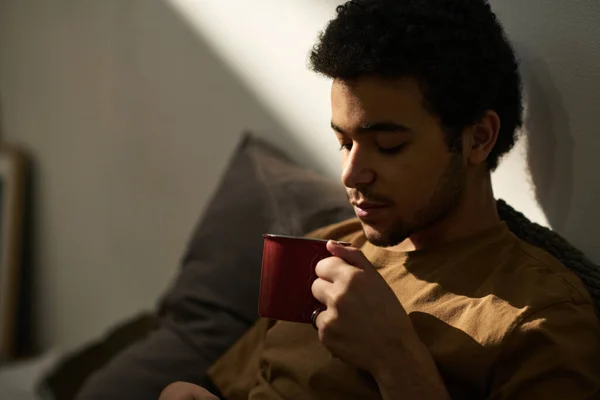 在他闲暇的时候在卧室用杯子喝热茶的年轻人的特写镜头 — 图库照片