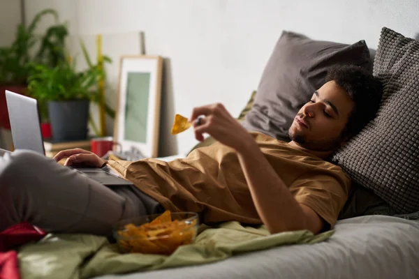 Szomorú Férfi Melankóliában Laptoppal Chipsszel Miközben Egyedül Fekszik Ágyon Hálószobájában — Stock Fotó