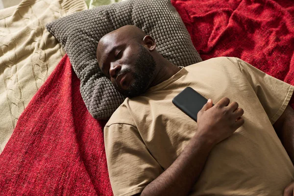 非洲裔美国人精疲力竭 躺在床上 拿着手机的高角照片 — 图库照片