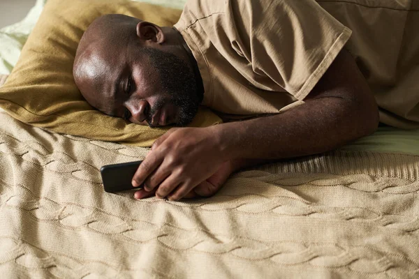 Afroamerykanin Leżący Łóżku Patrząc Ekran Swojego Smartfona Czeka Telefon — Zdjęcie stockowe