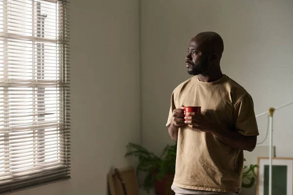 Africano Americano Homem Olhando Para Janela Com Expressão Pensativa Enquanto — Fotografia de Stock