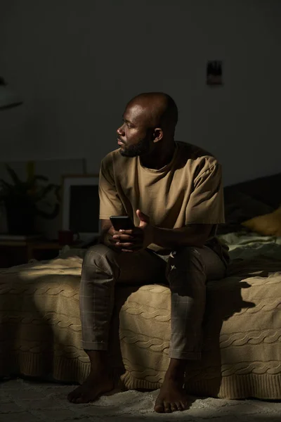 Afro Amerikaanse Man Zit Bed Met Mobiele Telefoon Denken Aan — Stockfoto