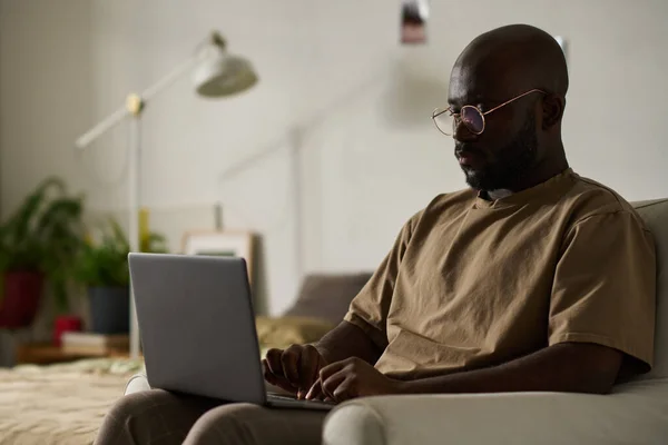 Afroamerykanin Koncentrujący Się Swojej Pracy Online Laptopie Siedząc Fotelu Pokoju — Zdjęcie stockowe