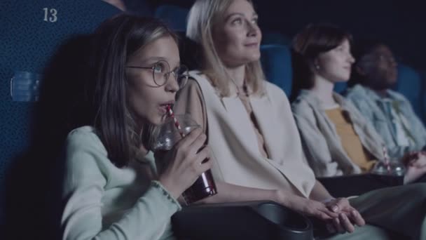 在电影院与母亲一起看电影时 年龄在十几岁的白人女孩戴着眼镜 一边喝可乐 — 图库视频影像
