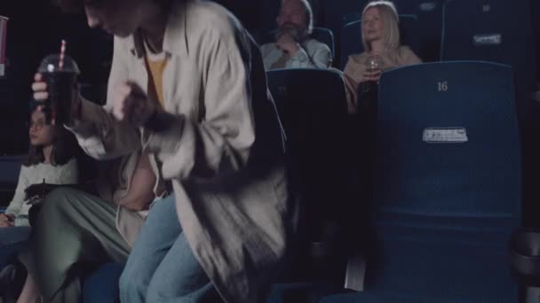 年轻的黑人男子和他的白人女友在电影院的座位上 吃爆米花 在电影开映前聊着天 — 图库视频影像
