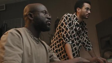 Genç Afrikalı Amerikalı bir adam şarkıcı ya da meslektaşına danışıyor ve stüdyoda birlikte yeni müzik kaydederken karıştırma tahtasındaki sesleri ayarlıyor.