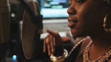 Mikrofonun önünde dikilen ve stüdyoda yeni albümler kaydederken yeni şarkılar söyleyen enerjik siyahi kadınların yakın plan görüntüleri.