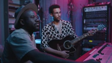 Genç kendine güvenen operatör, akustik gitarlı genç müzisyenin stüdyoda yeni bir müzik kaydı yapılırken genel müzik kompozisyonunu nasıl geliştireceğini anlatıyor.