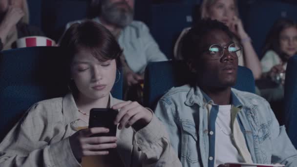 在和男朋友一起看电影时 年轻的Z型女性通过智能手机或上网发短信 — 图库视频影像