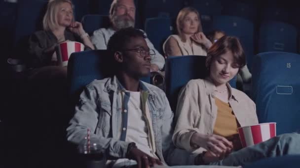 在电影院看电影的时候 年轻的黑人男人和白种女人牵着手恋爱 — 图库视频影像