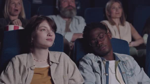 年轻的黑人在电影院看电影时睡着了 他的白人女友叫醒了他 — 图库视频影像