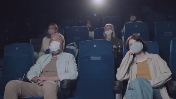 隔离期间 不同类别的男男女女戴着防护面具在电影院看电影 — 图库视频影像