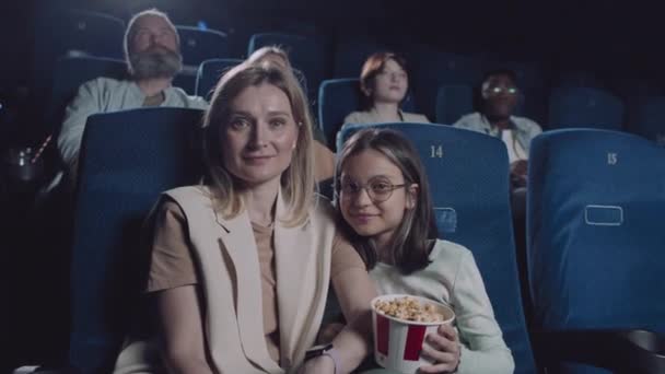 现代白人妇女及其未成年女儿坐在电影院大厅看着镜头的画像 — 图库视频影像