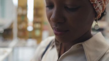 Genç siyah bir kadının, modern kozmetik süpermarketinde yeni el bakım ürünlerini test ederken ellerinin derisine besin kremi sürmesi.