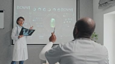 Afrika kökenli Amerikalı tıp çalışanı, konferansta olgun beyaz kadın konuşmacıya soru soruyor.