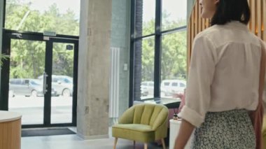 Kozmetik süpermarketinin çıkışına doğru güzellik ürünleriyle birlikte vitrinlerde dolaşırken günlük kıyafetlerle alışveriş yapan genç bayanın arka görünüşü