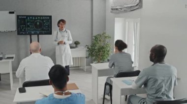 Olgun pratisyen, beyaz önlüklü, derste ders veren ya da tıp konferansında sunum yapan.