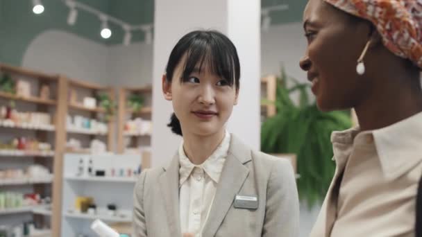 Junge Asiatische Verkäuferin Berät Kunden Eines Großen Kosmetikmarktes Und Beschreibt — Stockvideo