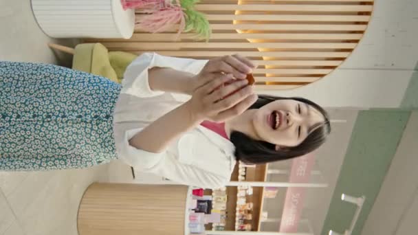 幸せな若いアジアの女性のお店の垂直ショットは クレジットカードをキャッチ それを見て カメラの前に立っている間 化粧品のスーパーマーケットでの購入のために支払う — ストック動画