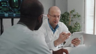 Kafkas doktorunun dijital tablet tutarken, meslektaşlarıyla tıbbi projeleri tartışırken seçmeli odak noktası.
