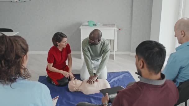 若い大人を教える成熟した医療労働者の高い角度ビューダミー上のCpr心臓マッサージを行う方法 — ストック動画