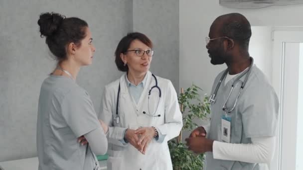 Gammal Allmänläkare Och Två Läkarstudenter Som Står Kontorsrum Och Diskuterar — Stockvideo