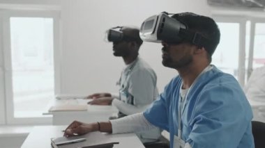VR kulaklık takan genç Hintli ve Afrikalı tıp öğrencileri ya da stajyerler modern tıp eğitimi kursunda ders alıyorlar.
