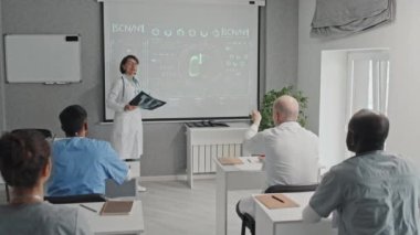 Yetişkin bir kadın pulmonoloğun X-ray iğnesi yapıp akciğer hastalıkları hakkında konferans vermesi. Bir tıp çalışanı ona bir soru soruyor.