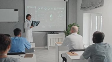 Göğüs röntgeni çeken olgun bir kadın pulmonolog konferansta ya da seminerde sunum yapıyor.