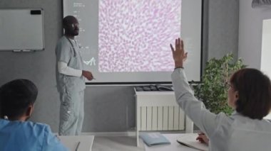 Afro-Amerikan konuşmacısına konferansta ya da seminerde sunum hakkında soru soran tanınmamış kadın doktor.