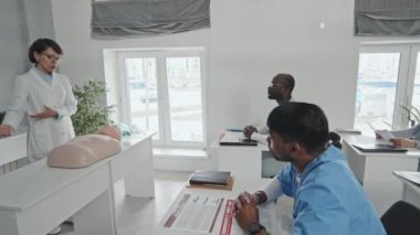 İlk yardım ve suni teneffüs hakkında konferans veren bir grup doktor ve hemşireyle birlikte çalışan yetişkin sağlık görevlilerinin el kamerası görüntüleri.
