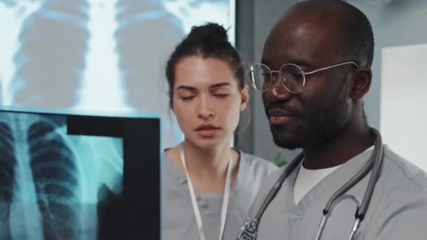 若いです大人アフリカ系アメリカ人男性と白人女性持っています病院でのインターンシップ胸X線撮影で作業 — ストック動画