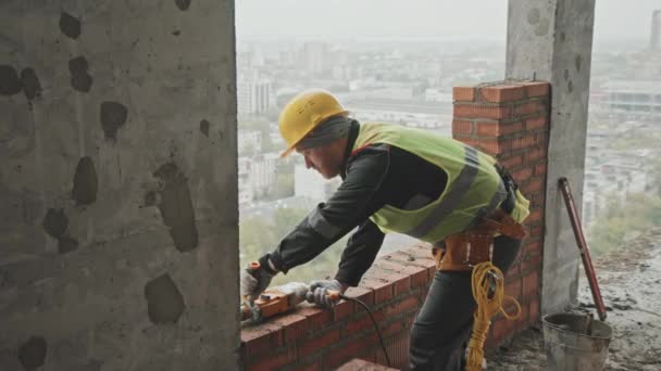 鉄筋コンクリートブロック内の穴を掘削する回転ハンマーを使用したひげそり白人建設労働者 — ストック動画