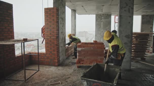 Długie Ujęcie Afroamerykańskiego Robotnika Budowlanego Mieszającego Pastę Zapraw Jego Kaukaskiego — Wideo stockowe